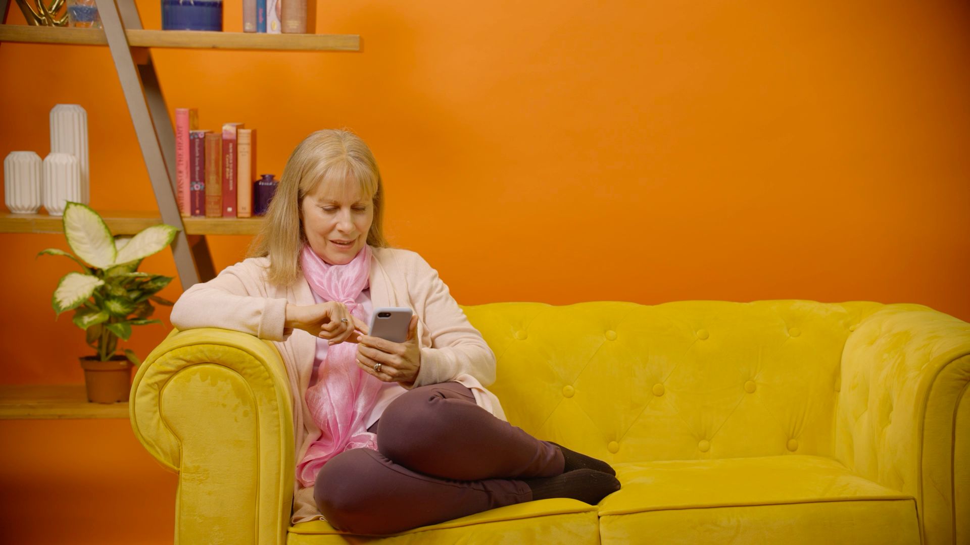 Lexie, one of the users from the W3C stories, sits on a couch with a phone in hand.
